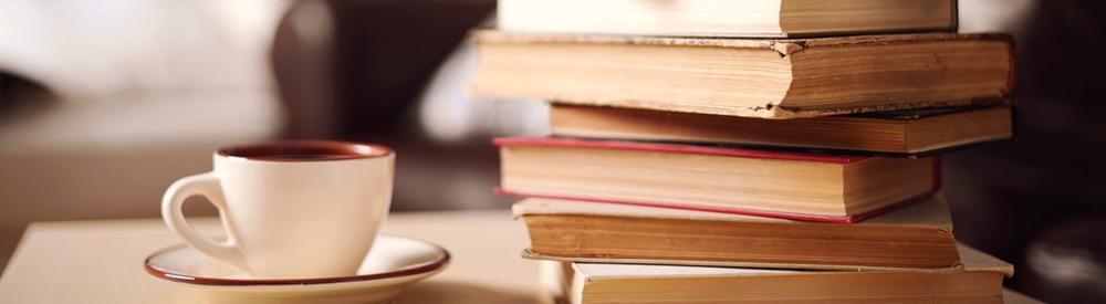 a stack of books next to a coffee cup in a saucer